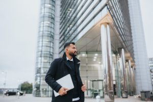 Man carrying a briefcase outside of a corporate building