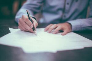 Person signs contract at desk with text overlay that states