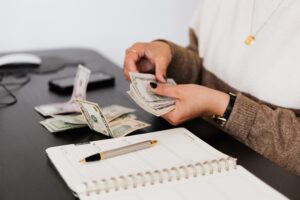 Person counting money at desk over planner