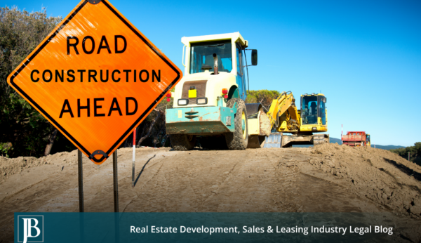 Orange "Road Construction Ahead" sign beside a roller and excavator grading a dirt roadbed, illustrating Florida's Turnpike Widening construction in Central Florida.