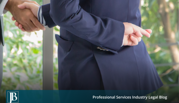 Business partner in a suit shaking hands while crossing his fingers behind his back, symbolizing a partner who breached their fiduciary duty.