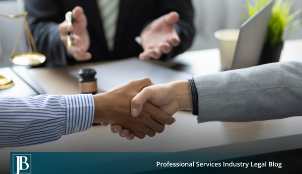 Two business professionals shaking hands across a desk with a gavel and scales of justice nearby, illustrating settlement of a Florida business dispute outside of court.