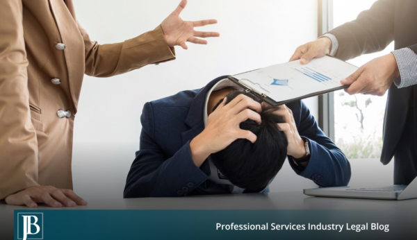 Minority business owner slumped over a conference table with his head in his hands while two majority owners hand him a financial report, illustrating a shareholder freeze-out dispute.