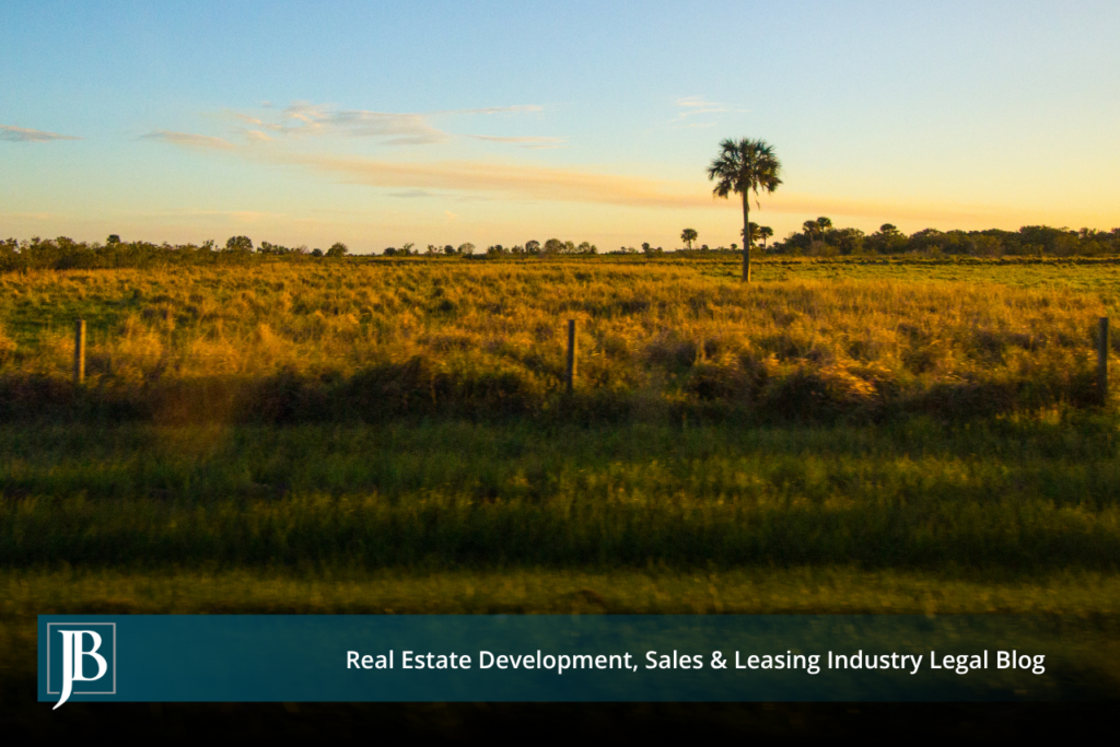 Sunset over open grassland, a wire fence, and a lone palm tree in the Everglades Agricultural Area near the EAA Reservoir site in western Palm Beach County, Florida.