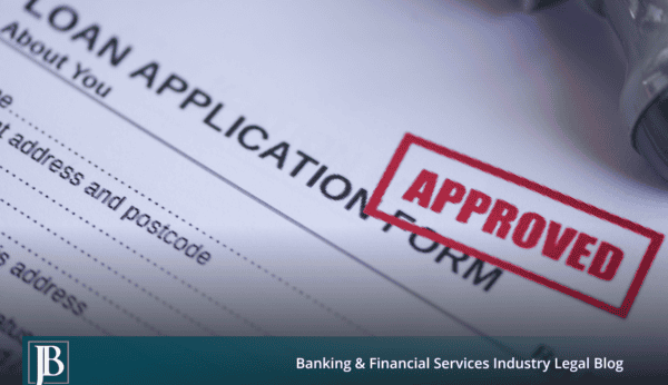 Close-up of a commercial loan application form stamped APPROVED in red ink, with a rubber stamp resting beside it.