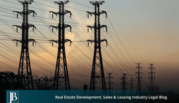 Silhouetted high-voltage electric transmission towers and power lines stretching across a Florida sky at sunset, illustrating a Duke Energy transmission line easement corridor.