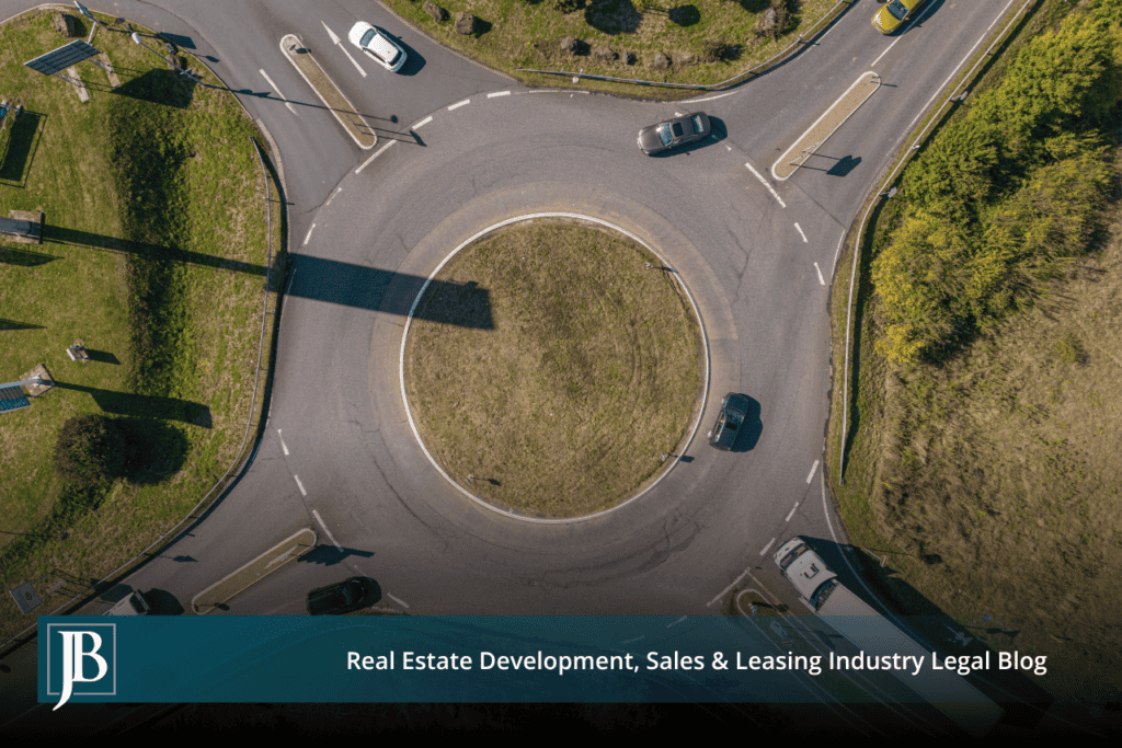 Aerial view of a completed highway roundabout with a landscaped center island and approach lanes, illustrating the access and parking changes commercial owners face from a roundabout project on SR 434 in Seminole County.