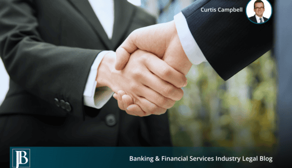 Two business professionals shaking hands outside an office building, a handoff of a business that can raise successor liability.