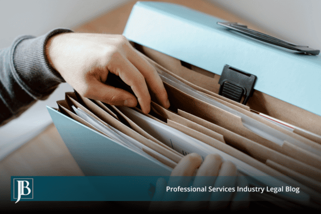 Hand pulling a file from an expanding folder of documents, illustrating document collection and production during discovery in business litigation.