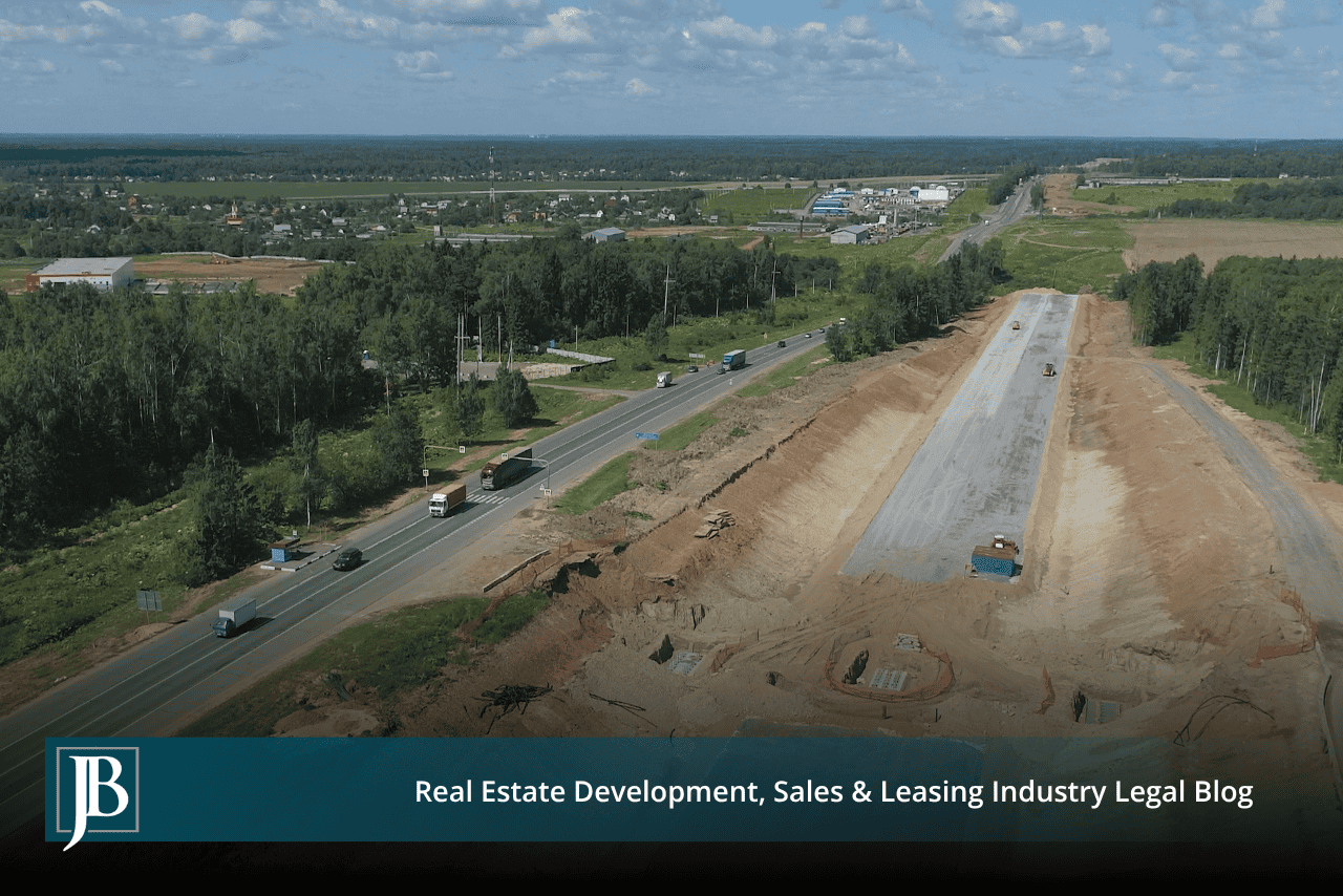 Aerial view of new roadbed cut beside a busy divided highway, illustrating right-of-way work on Branford Highway in Lake City