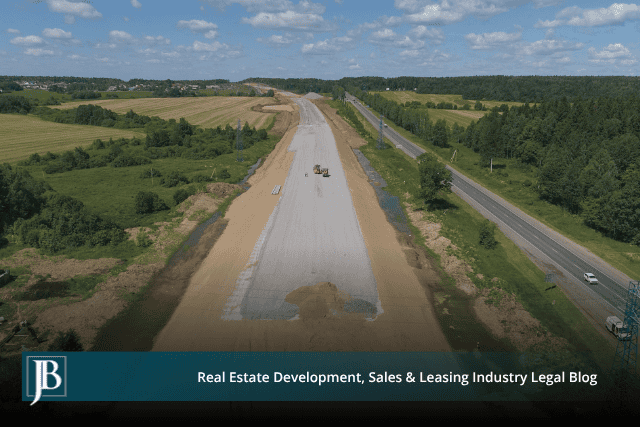 Aerial view of a new roadbed beside a highway, illustrating road work that can bring owners to a Tampa eminent domain attorney