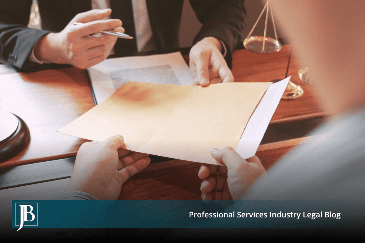 Business owner handing a manila envelope of documents across a desk to a lawyer during a first meeting.