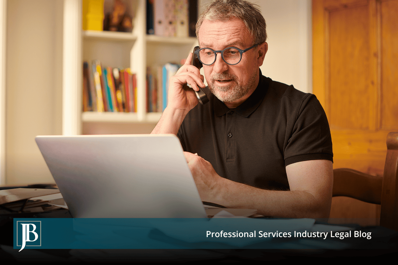 Man in glasses on the phone at his laptop, illustrating a business owner responding to a breach of contract complaint