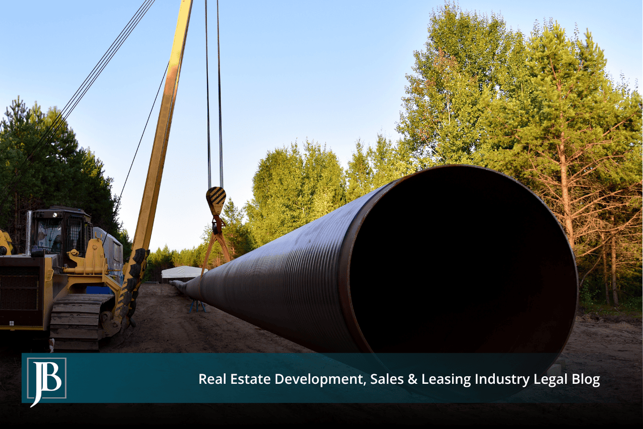 Large steel pipe section hoisted by a pipelayer crane, illustrating an FGT Phase IX pipeline easement