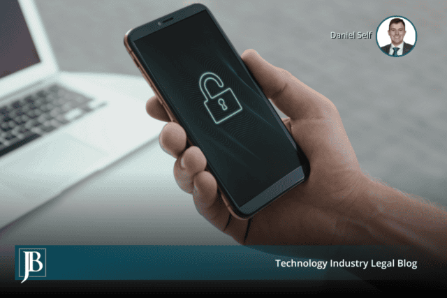 Hand holding a smartphone with a glowing unlocked padlock on screen beside a laptop, illustrating Florida wiretapping law and website tracking