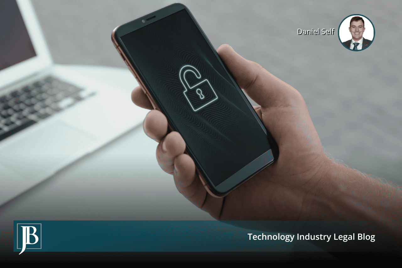 Hand holding a smartphone with a glowing unlocked padlock on screen beside a laptop, illustrating Florida wiretapping law and website tracking
