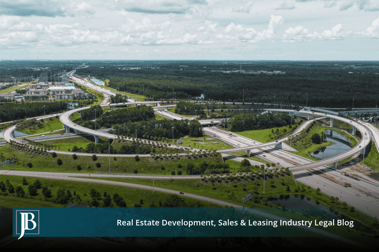 Aerial view of a highway interchange with curving flyover ramps through pine forest, illustrating FDOT projects that need land