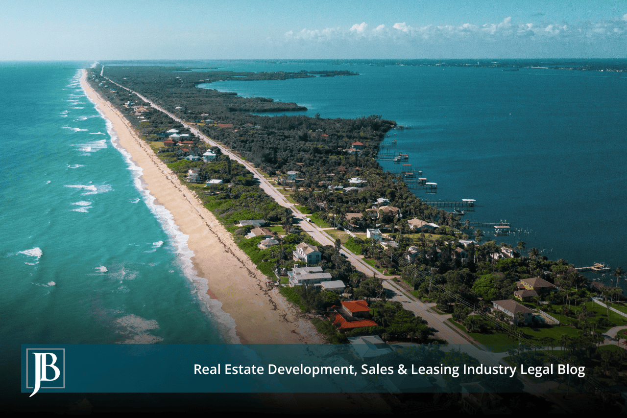 Aerial of a barrier island with a beach, a road, and lagoon docks, illustrating when to call a Melbourne eminent domain attorney