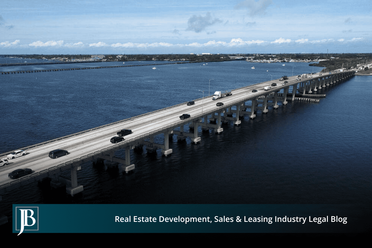 Aerial view of the four-lane DeSoto Bridge over the Manatee River, with cars and a semi truck crossing between the two shores